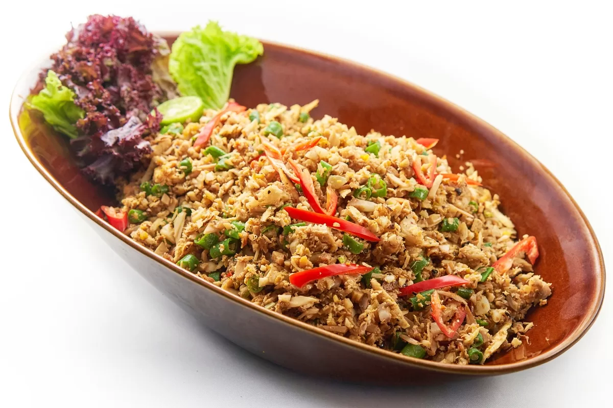 Lawar with long beans, young jackfruit, and minced chicken, served in a bowl and garnished with curly lettuce.