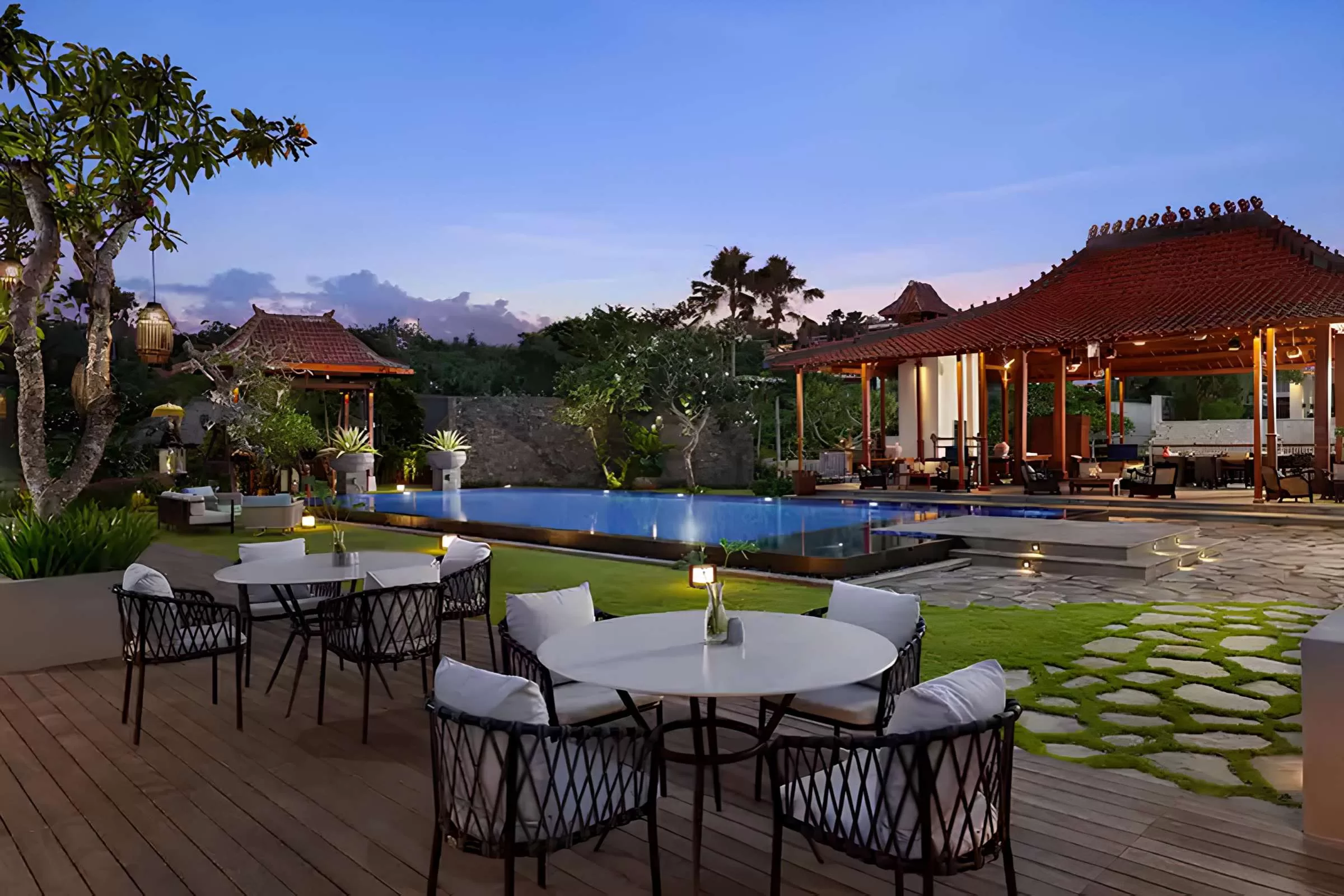 Tulou Bali Jimbaran luxury villa with a pool, outdoor dining area, and traditional pavilion under an afterglow sky.