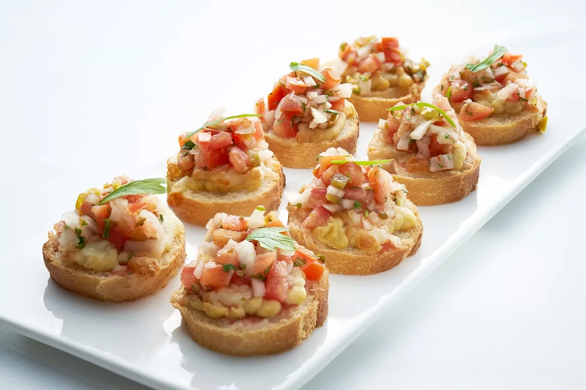 Mexican bruschetta or molletes on toasted garlic baguette slices with refried beans and fresh tomato salsa.