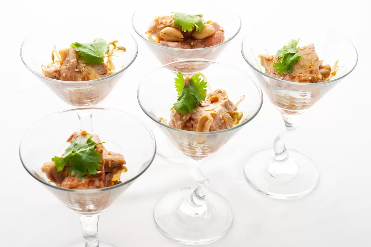 Spicy chicken with tender chicken in chili oil sauce, topped with peanuts and fresh garnish.