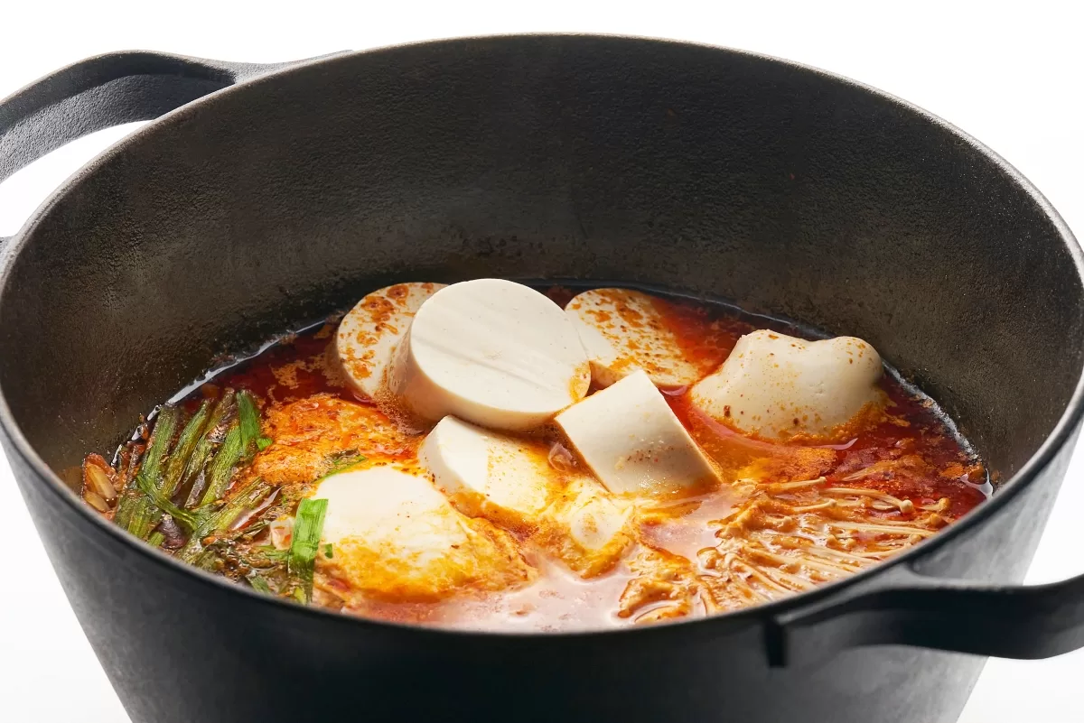 Sundubu, Korean stew with tofu and enoki mushrooms simmered in a spicy clam-based broth.