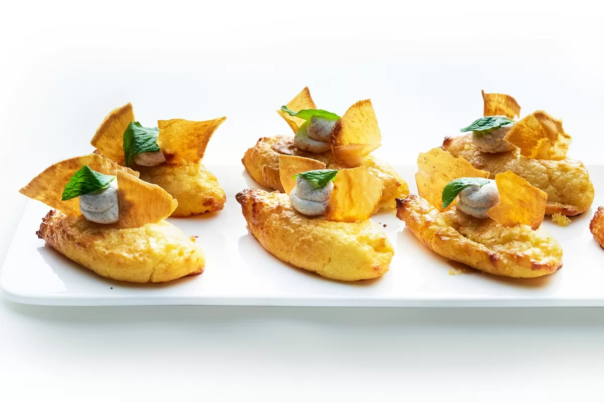 Sweet potato cake with a golden baked crust, topped with crispy chips and a creamy topping.