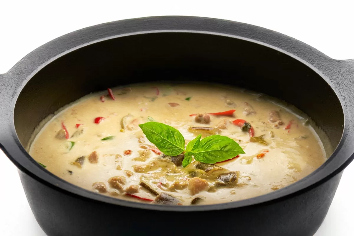 Thai green curry with creamy coconut sauce, garnished with fresh basil.