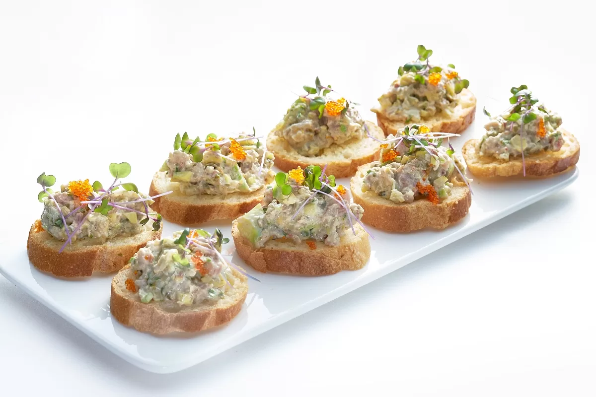 Tuna tartare served on toasted bread slices, topped with microgreens.