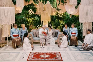 A newlywed couple in traditional attire practices Javanese wedding ritual witnessed by their parents at the Moonlight Garden.