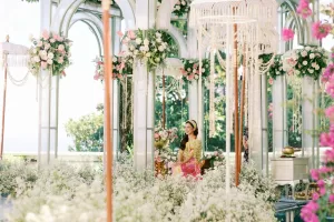 Bride in traditional attire surrounded by lush floral and tedung decoration in an elegant pavilion setting at Tirtha Uluwatu.