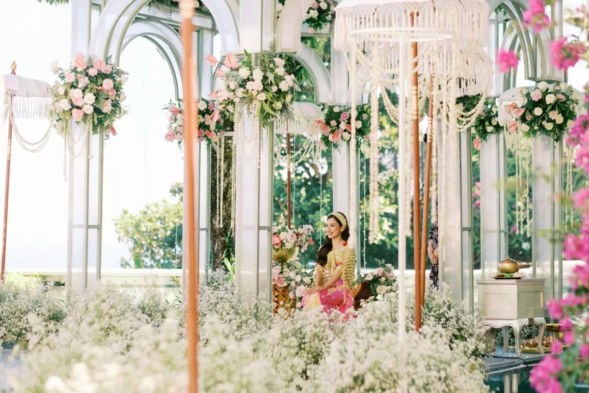 Bride in traditional attire surrounded by lush floral and tedung decoration in an elegant pavilion setting at Tirtha Uluwatu.