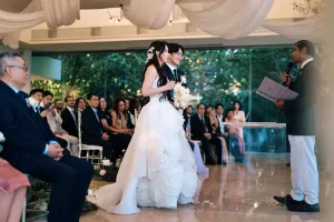 Bride and groom stand at the altar as an officiant reads, witnessed by the guests in the Heaven Room at Tirtha Uluwatu.
